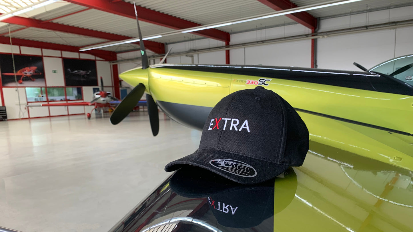 Produktbild der Extra Cap. Abgelegt auf dem linken Flügel einer Extra 330 SC. 